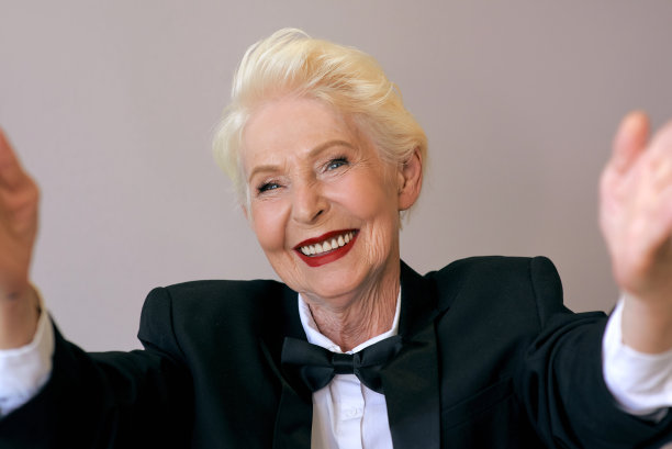 穿着燕尾服的时尚成熟的老年女性，用手机视频通话或自拍。图片下载