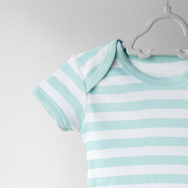 在衣架上为新生儿准备的带条纹的干净衣服。文本。服装的概念，母性，时尚。图片下载