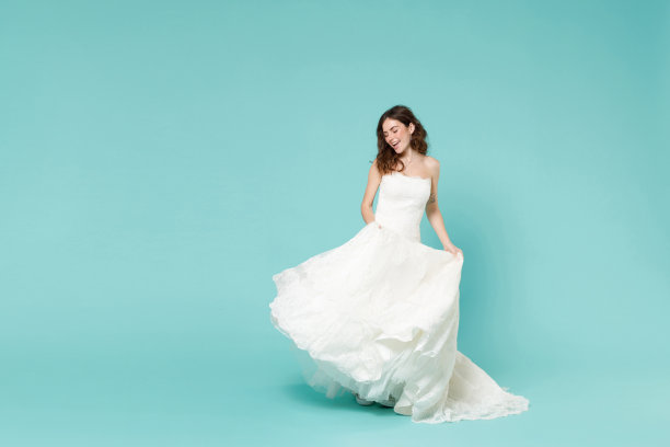 欢快漂亮的新娘20多岁的全长侧面视图美丽的白色婚纱跳舞有乐趣孤立在蓝色绿松石背景工作室肖像。庆典庆典派对概念。图片下载