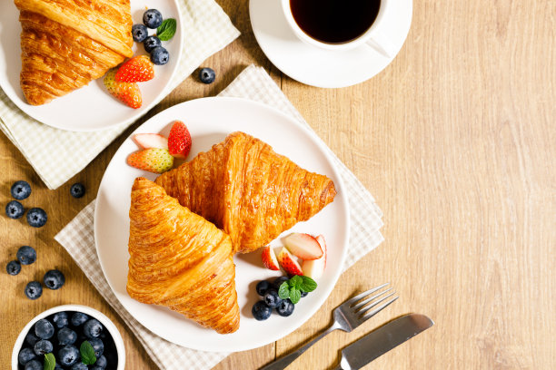 早餐：牛角包和新鲜浆果，木桌背景图片下载