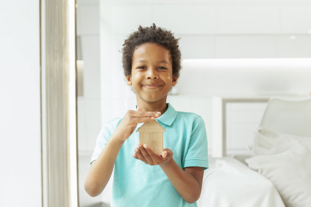 可爱的小男孩在家里展示木制房子玩具图片下载