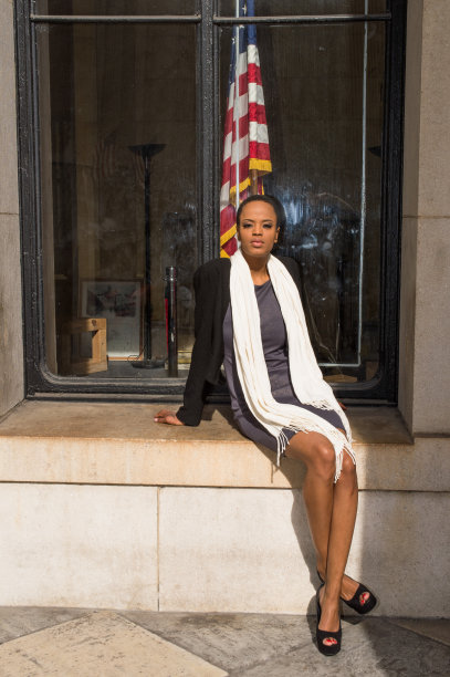 一位年轻的黑人女商人正坐在办公室外的一个大窗框上休息。“r图片下载