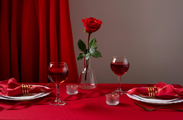 浪漫的餐桌，白色的餐具，红色的餐巾，红酒和蜡烛。情人节或浪漫晚餐的概念。浪漫晚餐。图片下载