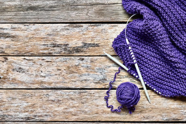 紫色羊毛纱球，里拉围巾和木制针织针在桌子上从上面看。爱好工艺背景与文字空间。针织概念，针线活。佩里的颜色。图片下载