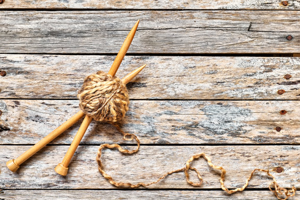 桌子上有一团羊毛纱线和木制编织针。爱好工艺背景与文字空间。针织概念，针线活。前视图。图片下载