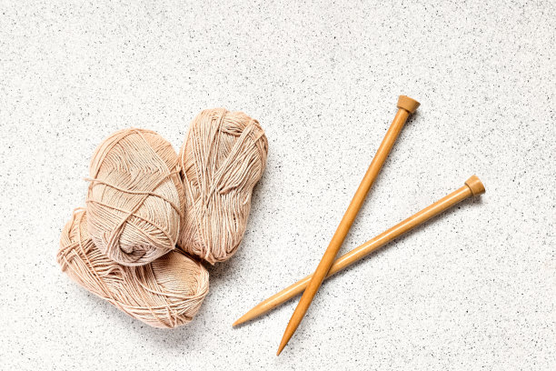 球的羊毛纱和木制针织针在浅灰色的背景视图从上面。爱好工艺背景与文字空间。针织概念，针线活。图片下载