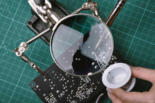 电子维修服务，技术员用烙铁和锡固定电子线路板，放大镜在焊锡架上。图片下载