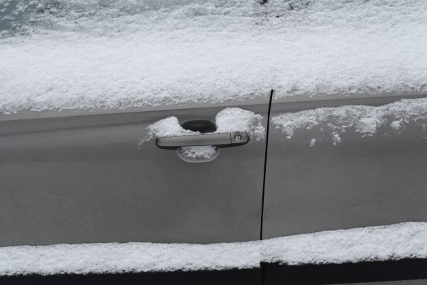 靠近冰冻的冬季汽车覆盖积雪，查看侧门与门锁门把手图片下载