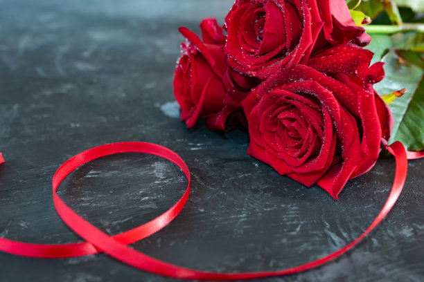 灰色石板上带着丝带的红玫瑰图片下载