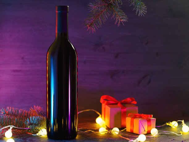 浪漫的除夕晚餐概念。情人节的概念。两个礼品盒和一瓶红酒。霓虹灯木制背景复制空间图片下载