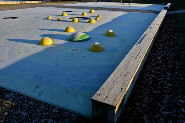 操场的白色橡胶表面上有黄色的球和彩色的斑点在霜冻的人类脚印。凸起的镜头，如球，木凳和圆形的蹦床沉入地形。图片下载