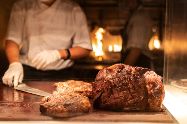 站在服务站后面的厨师烤牛排和和牛，背景是火焰。图片下载