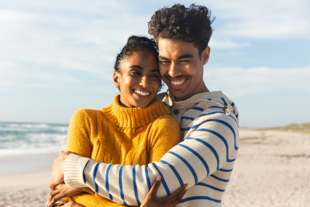 阳光明媚的一天，在沙滩上，一个快乐的混血儿拥抱着他的女朋友图片下载