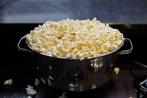 装满爆米花的不锈钢锅。关注锅的边缘。软焦点的背景图片下载