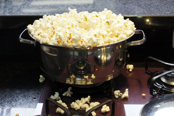 装满爆米花的不锈钢锅。关注锅的边缘。软焦点的背景图片下载