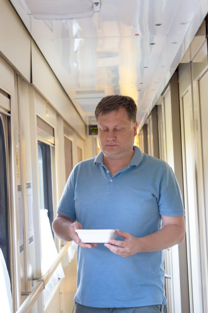 一名男子拿着热方便面沿着行驶的火车走廊慢慢走着图片下载