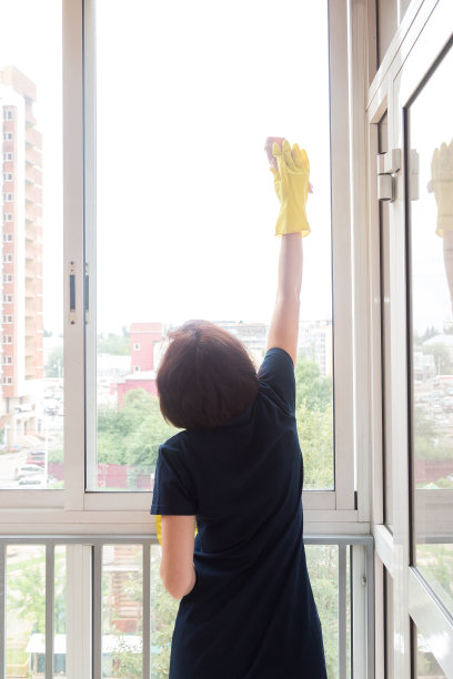 一位身材矮小的妇女吃力地清洗阳台上的高窗户图片下载