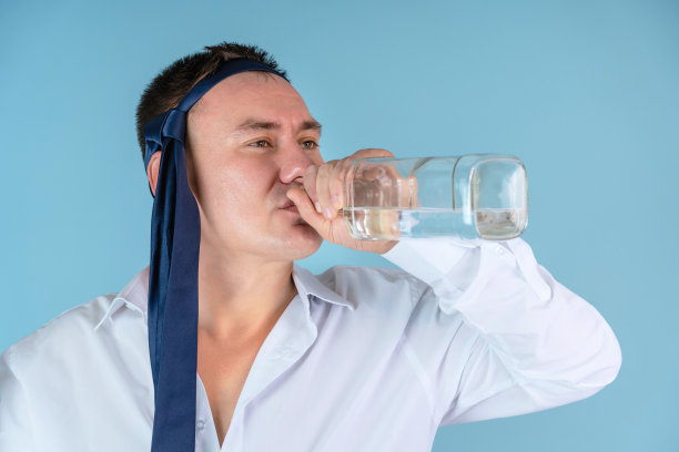 经理头上系着领带，站在蓝色的背景上喝着酒图片下载
