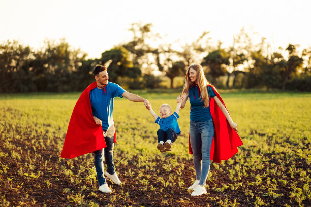 欧洲超级家庭概念，户外，慈爱的父亲抱着脖子，超级英雄家庭在日落时分奔跑在大自然中图片下载