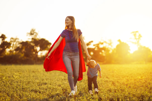 超级妈妈和她的儿子正在向前跑。欢乐的家庭，身着红色斗篷的超级英雄图片下载