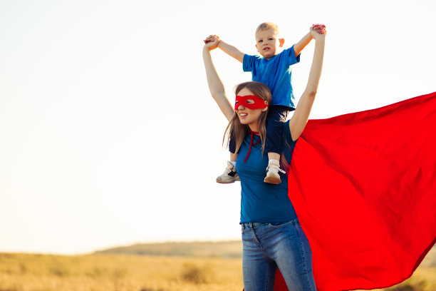 快乐的妈妈带着穿着超级英雄服装的儿子一起扮演超级英雄做着向前向上的手势图片下载