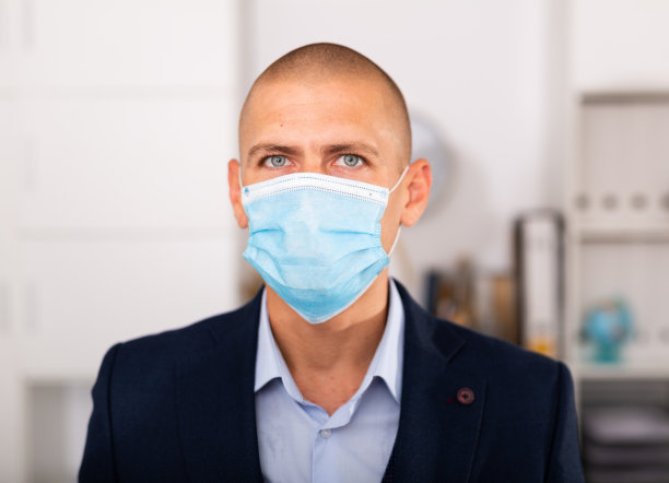 戴着医用口罩的经理站在现代办公室里图片下载