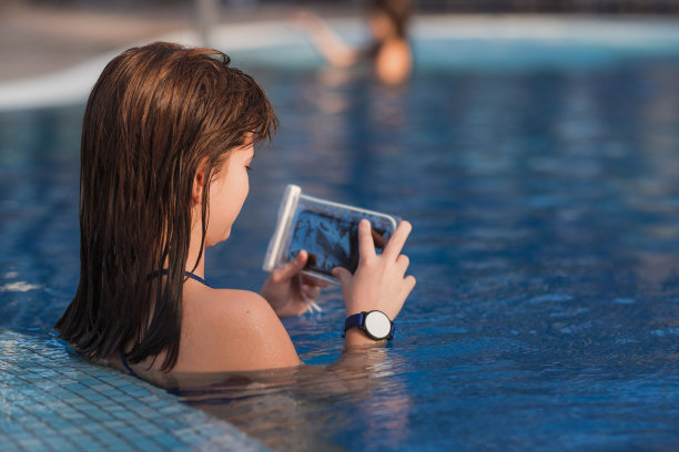 女孩在游泳池放松的时候把智能手机装在塑料袋里图片下载
