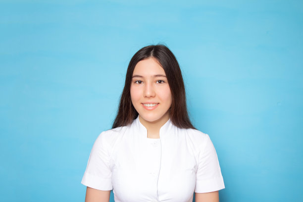 年轻美丽的亚洲女医生或护士在白色的医疗大衣孤立在蓝色的背景上。医学和保健概念。副本的空间。图片下载