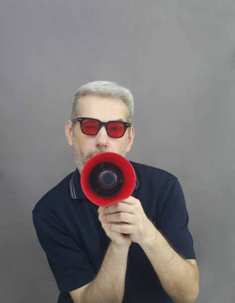 戴着红眼镜的中年男人对着扩音器大喊大叫图片下载