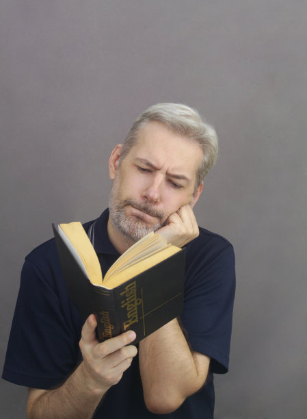 满头白发、留着胡子的睿智的中年男子正严肃地读着英语课本。图片下载
