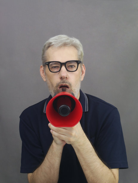 戴着红眼镜的中年男人对着扩音器大喊大叫图片下载