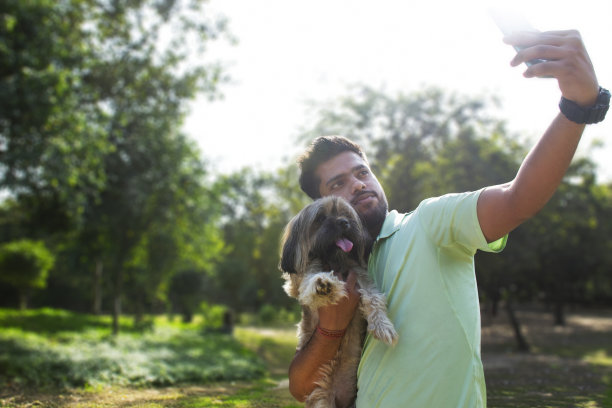 一个年轻人和狗在公园里自拍图片下载