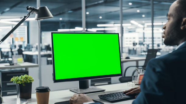 成功的黑人女商人坐在办公室用绿屏笔记本电脑工作。使用色度键显示的非裔美国商人。在肩射图片下载