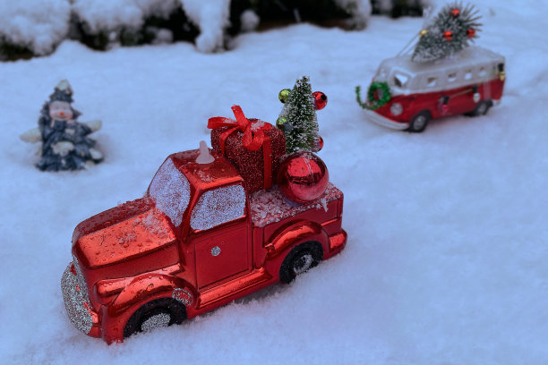 红色的汽车载着一棵圣诞树在雪地里。圣诞节和冬季假期的概念图片下载