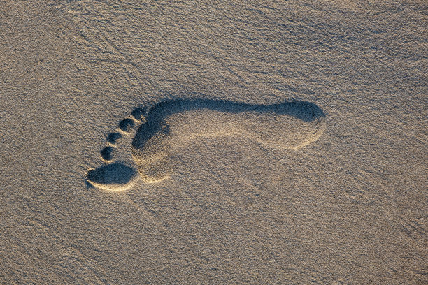 赤足的脚印在沙滩上，沙地上有副本空间图片下载