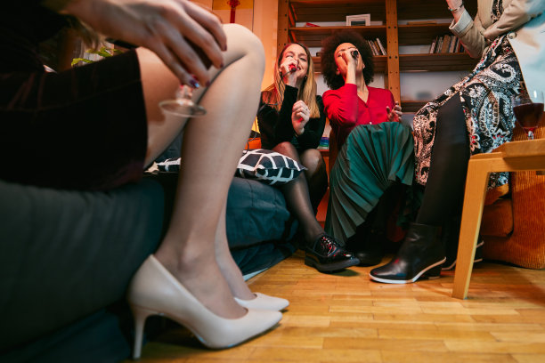 快乐的多元文化朋友坐在家里，笑着，唱着，在卡拉ok之夜玩得很开心。图片下载