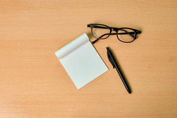 从俯视图可以看到一张白纸、一支笔和一副眼镜放在一张木头桌子上。工作图片下载