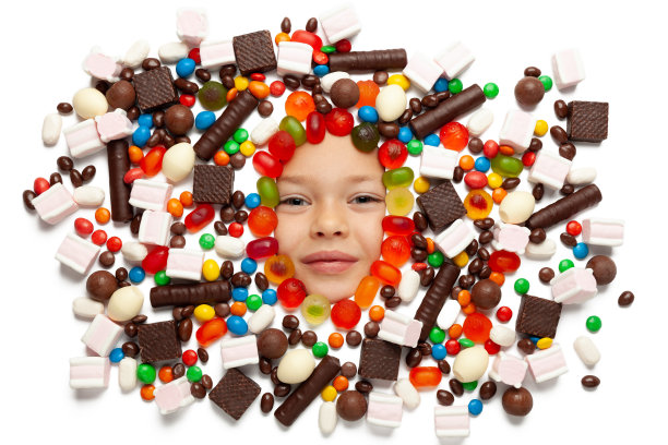 一个女孩的肖像与各种糖果在一个白色的背景。节日，糖果的享受。图片下载