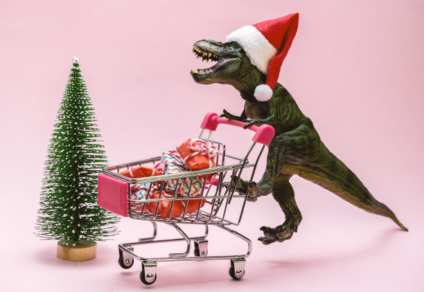 可爱的恐龙，购物车里装满了粉红色背景上的礼品盒。购物的概念。图片下载