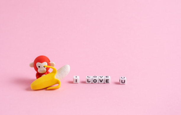 一只拿着香蕉的小猴子，粉红色的背景上写着我爱你。最小的情人节贺卡。图片下载