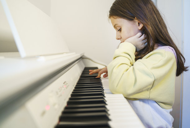 可爱的小女孩在家里弹钢琴图片下载