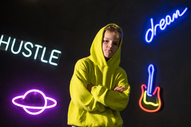 霓虹灯招牌背景上的时尚少年图片下载