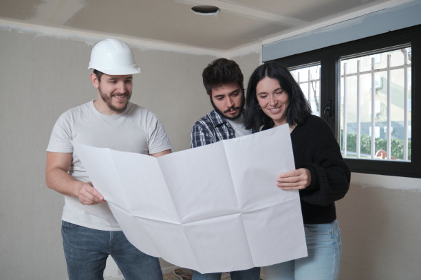 建筑师向感兴趣的年轻夫妇展示公寓的建筑蓝图。图片下载