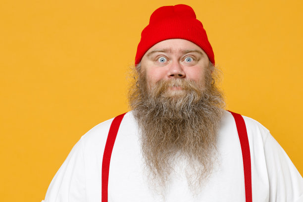 胖乎乎的胖胖胖的超重吃惊蓝眼睛大胡子白人男子30多岁大肚子穿白色t恤红色帽子吊带看着相机孤立在黄色背景的工作室肖像。图片下载