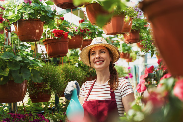 戴着帽子和手套的女园丁在温室里工作图片下载