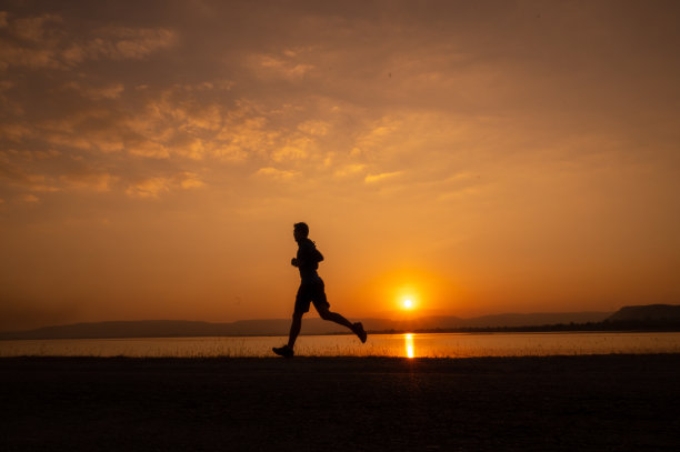 一个男人跑着剪影日落在湖和山图片下载
