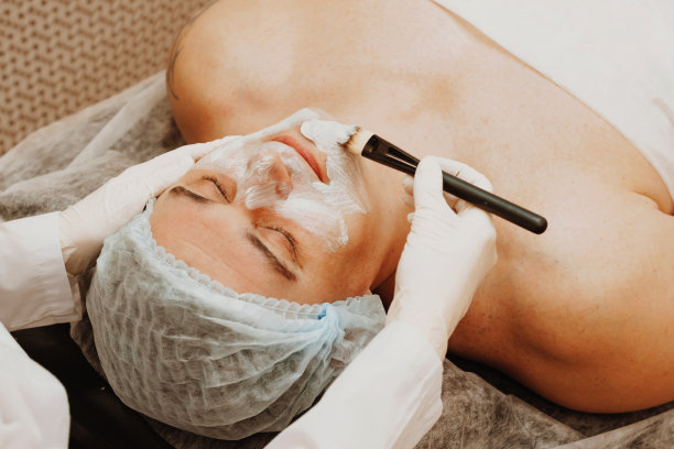 美容师在年轻人脸上敷磨砂面膜，水疗美容院。对男性身体和面部护理的概念图片下载