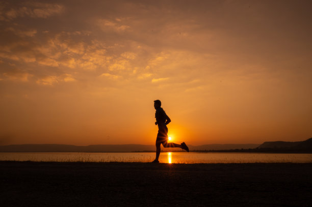 一个男人跑着剪影日落在湖和山图片下载