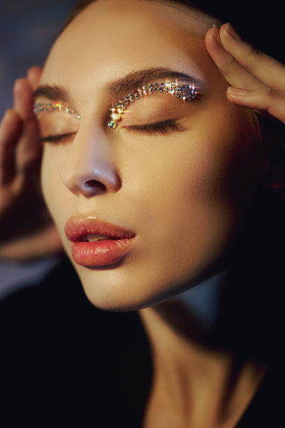 美丽的眉毛女人，莱茵石眼睛，专业化妆眉毛在女人脸上。眼睑眉毛上闪亮的水钻图片下载