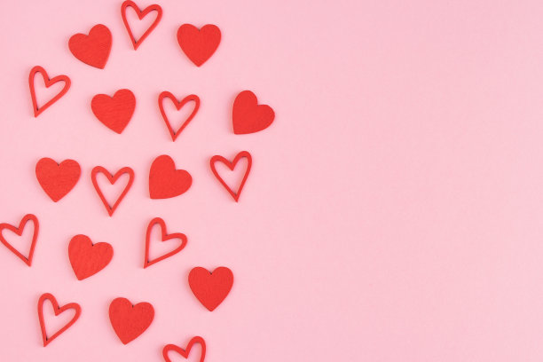 粉红色纸板背景上的红色木制心。副本的空间。情人节和母亲节。图片下载